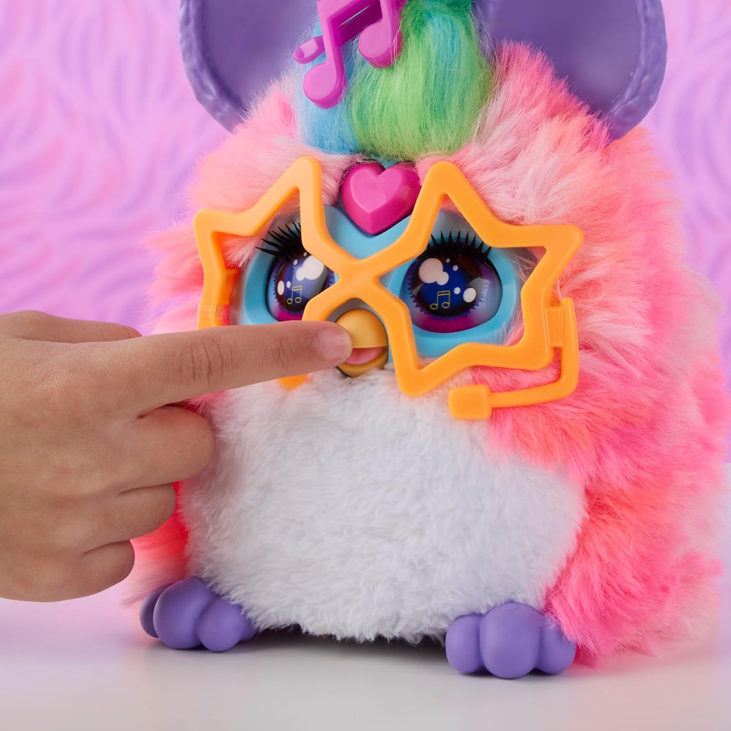 A hand pressing the front of a Furby Vibes plush to activate it