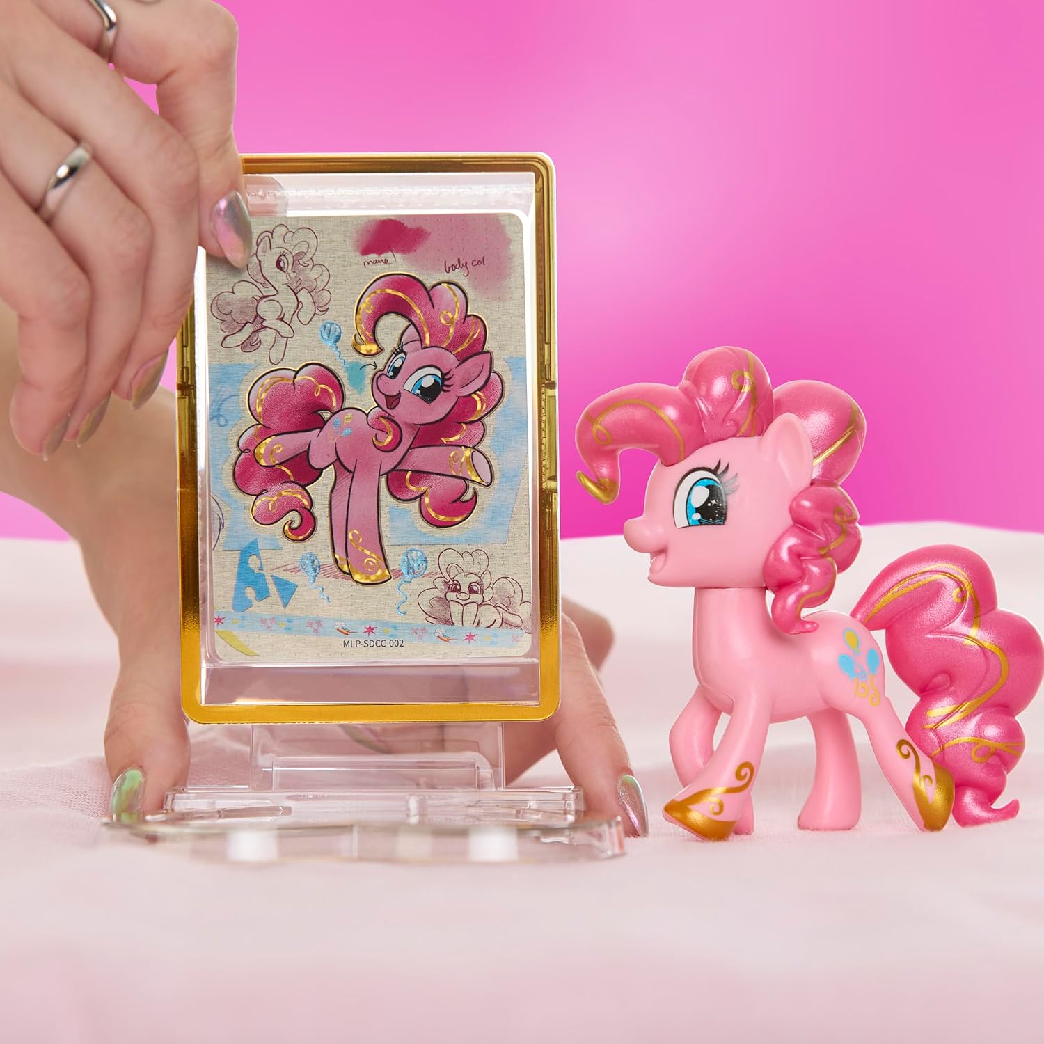 Pinkie Pie figure beside her Amy Mebberson trading card in a gold display case