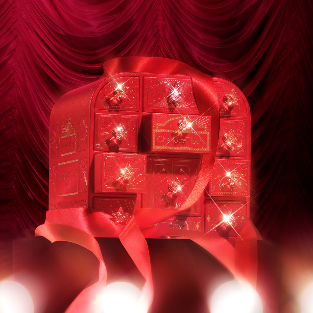 The 2026 Charlotte Tilbury advent calendar tied with a ribbon against a red velvet curtain backdrop