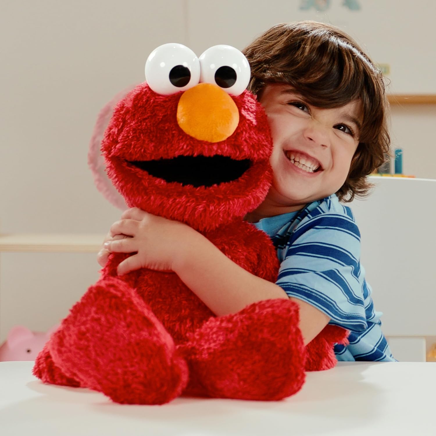 A young child hugging the 18-inch Tickle Me Elmo Giggle Max plush